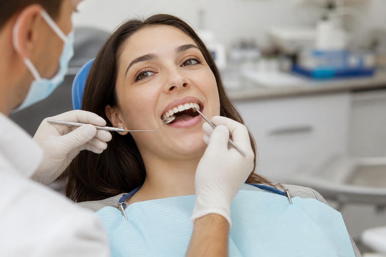 Dentist examining a smiling patient’s teeth with dental tools