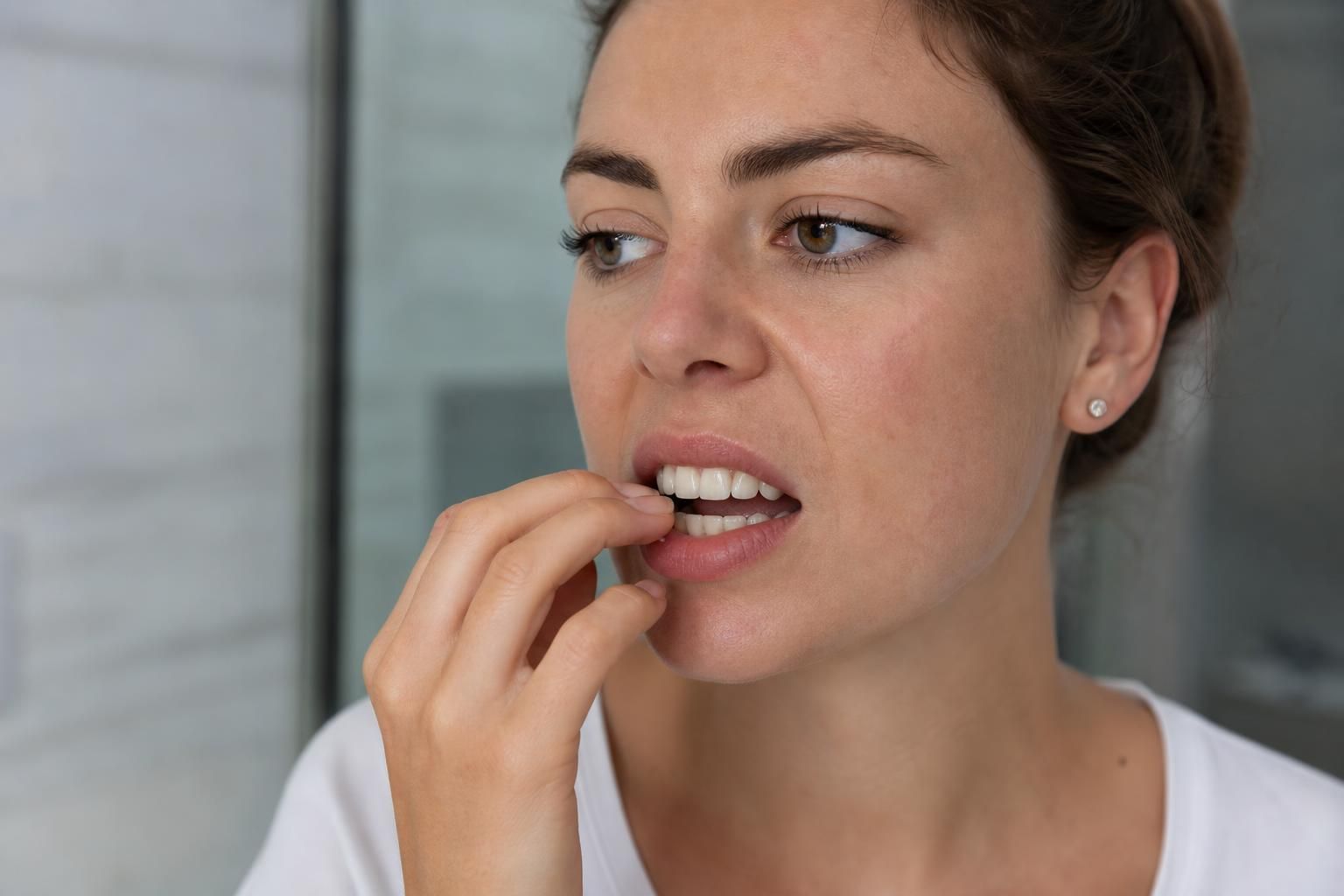 Woman biting her fingernail with her teeth